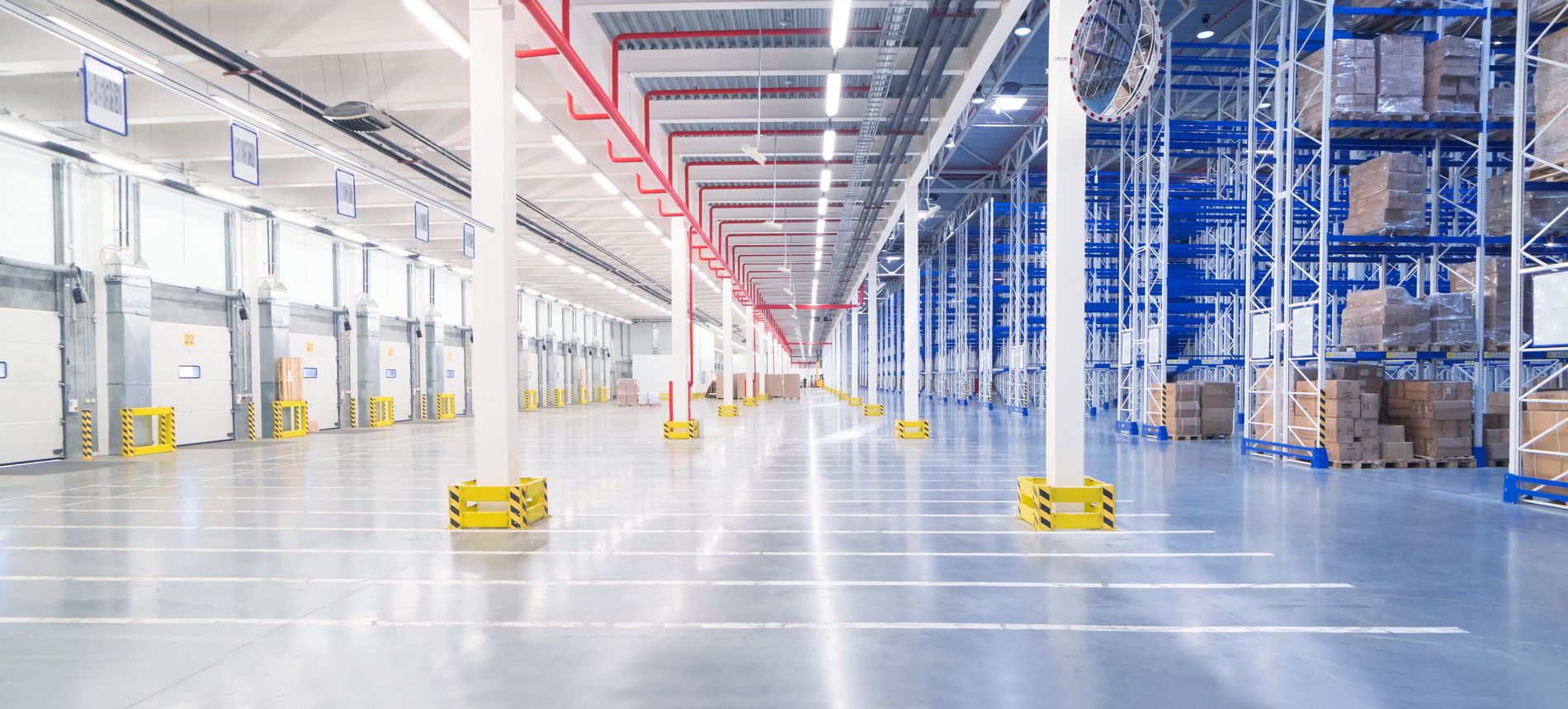 Huge distribution warehouse with high shelves and loading gates.